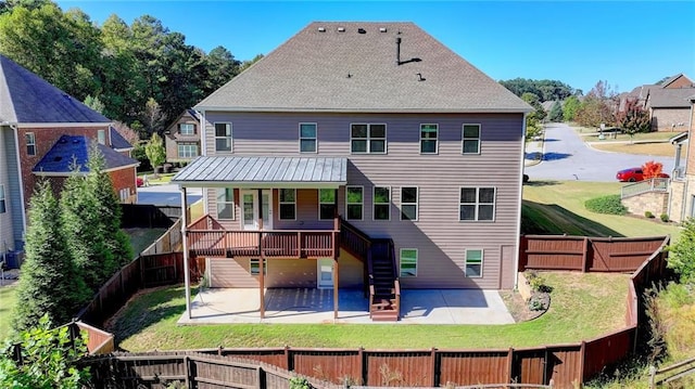 rear view of property featuring a wooden deck, a patio area, and a lawn