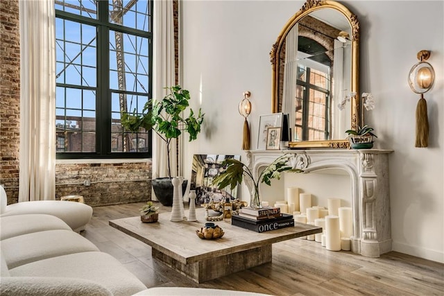 living area featuring a high ceiling, brick wall, a fireplace, and light hardwood / wood-style floors