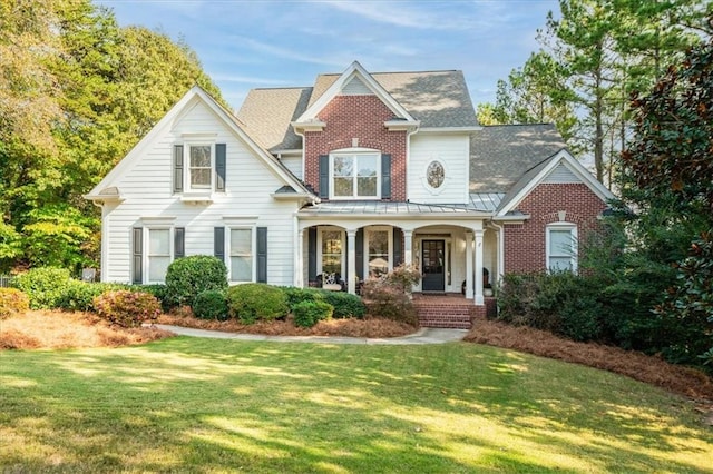 view of front of house featuring covered porch, a front lawn, and brick siding