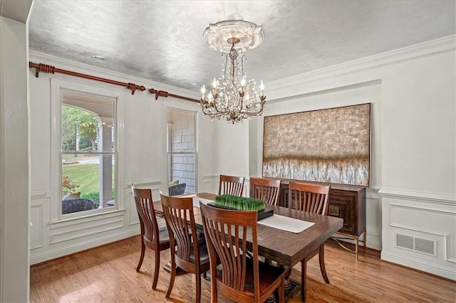 dining space featuring hardwood / wood-style flooring, crown molding, and an inviting chandelier