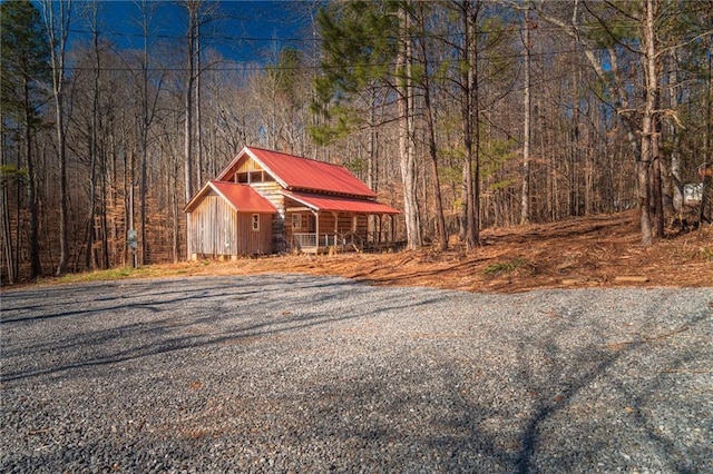 view of outdoor structure with an outbuilding, driveway, and a wooded view