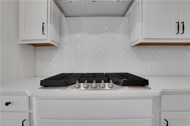 kitchen with light countertops, backsplash, white cabinetry, and range hood