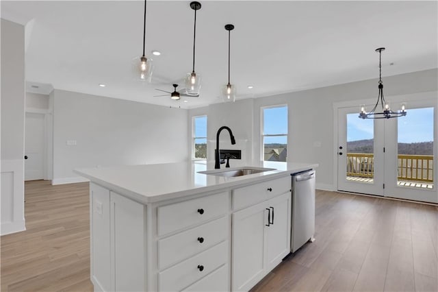 kitchen with white cabinets, dishwasher, an island with sink, light countertops, and a sink