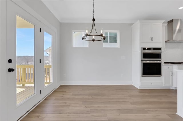 kitchen featuring wall chimney range hood, stainless steel double oven, dark countertops, and white cabinets