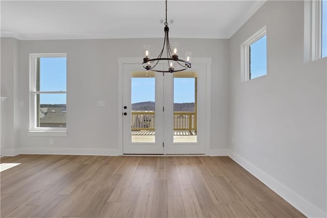 unfurnished dining area with light wood-type flooring, a wealth of natural light, and a notable chandelier