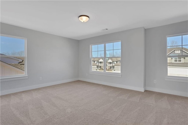 unfurnished room featuring light colored carpet, plenty of natural light, and baseboards