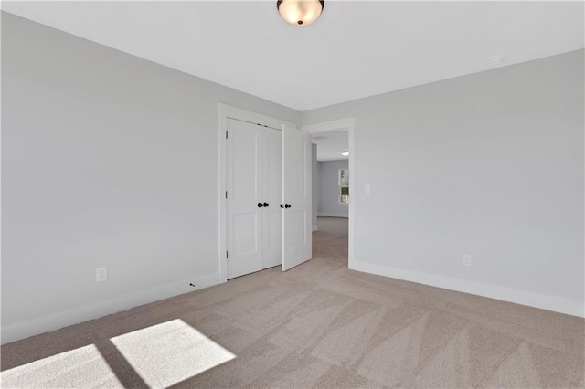 empty room featuring light colored carpet and baseboards