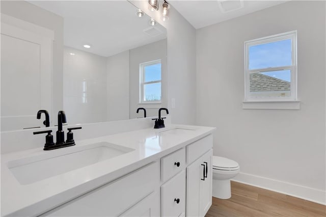 bathroom featuring baseboards, a sink, toilet, and wood finished floors