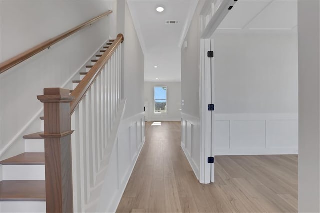 hallway with a wainscoted wall, recessed lighting, visible vents, a decorative wall, and light wood-style flooring