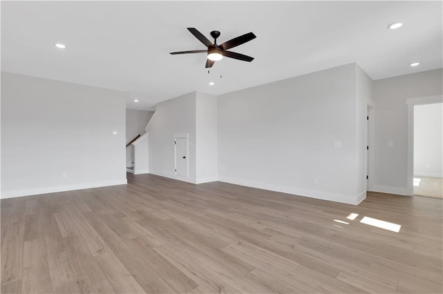 unfurnished living room featuring ceiling fan, stairway, light wood-style flooring, and recessed lighting