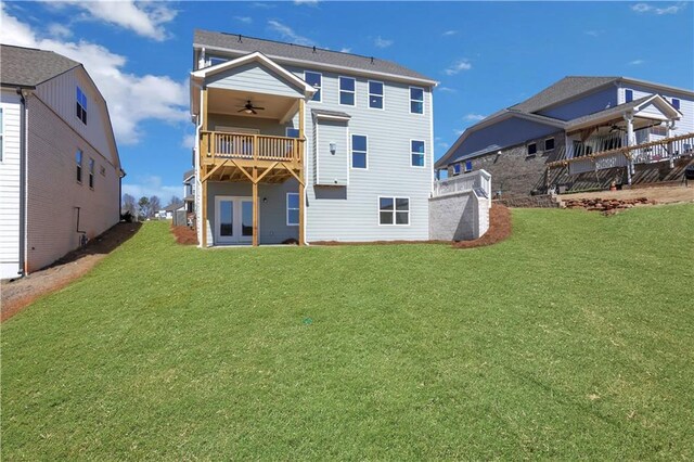 rear view of house with a lawn, a balcony, and a ceiling fan