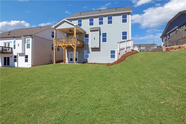 rear view of property featuring a lawn and a ceiling fan