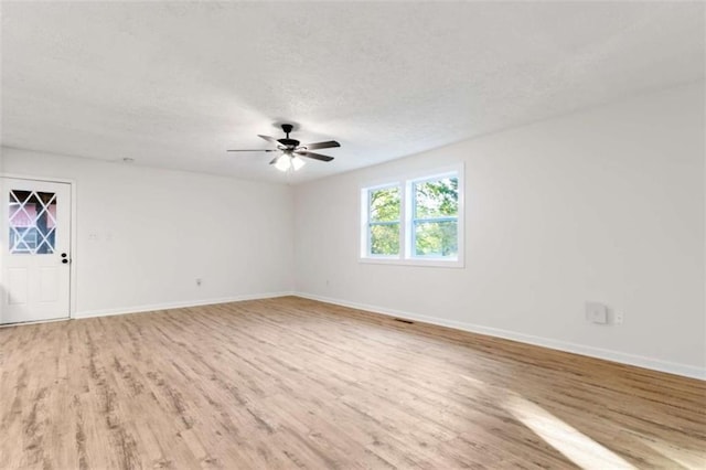 spare room with baseboards, a ceiling fan, wood finished floors, and a textured ceiling