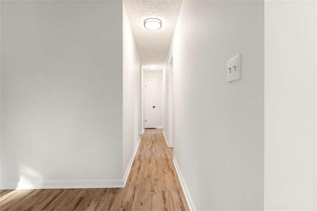 hall featuring light wood-type flooring and baseboards