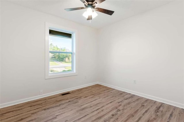 spare room featuring baseboards, a ceiling fan, wood finished floors, and visible vents