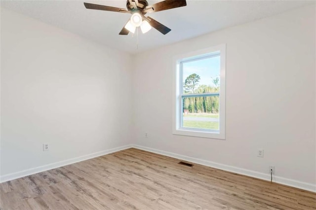 unfurnished room with wood finished floors, visible vents, and baseboards
