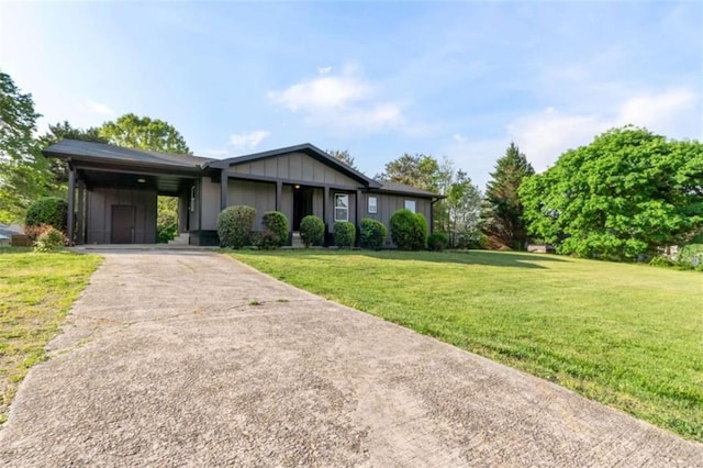 single story home with board and batten siding, driveway, a front lawn, and a carport