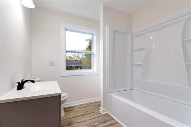 full bath featuring toilet, shower / bathing tub combination, baseboards, wood finished floors, and vanity