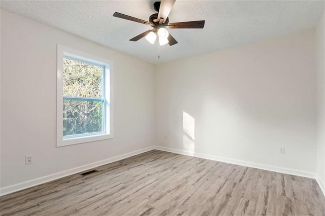 spare room featuring visible vents, baseboards, wood finished floors, and a textured ceiling