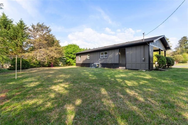 back of house featuring board and batten siding and a lawn