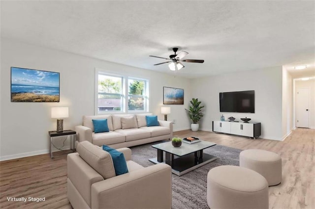 living room with baseboards, wood finished floors, a textured ceiling, and ceiling fan