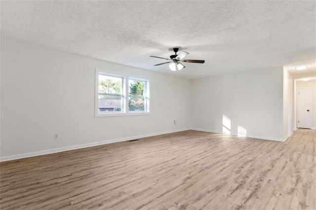 spare room featuring light wood finished floors, a ceiling fan, baseboards, and a textured ceiling