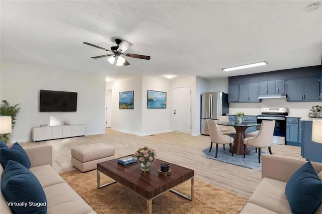 living area featuring ceiling fan, baseboards, and light wood finished floors