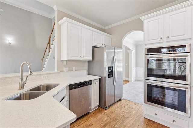 kitchen with white cabinetry, sink, stainless steel appliances, light hardwood / wood-style floors, and ornamental molding