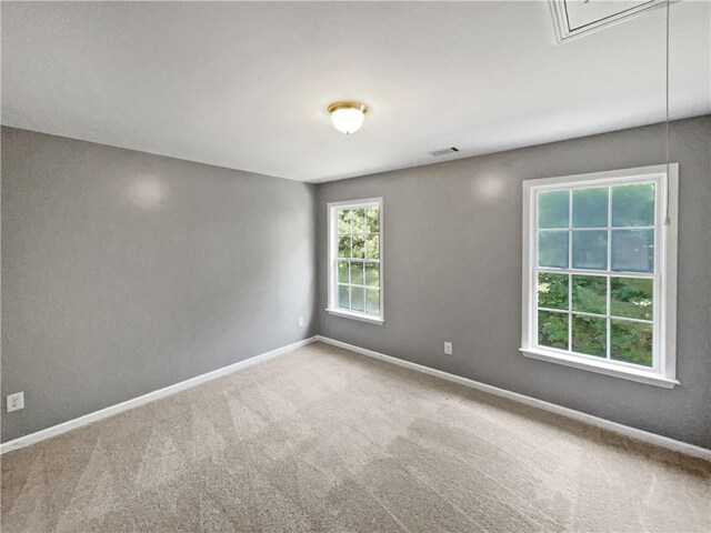 spare room with visible vents, carpet floors, attic access, and baseboards