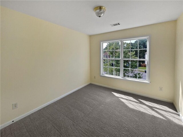 carpeted spare room featuring visible vents and baseboards