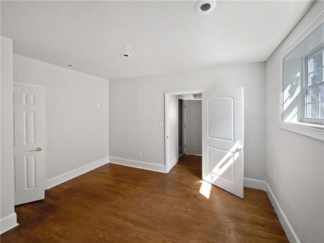 unfurnished room featuring baseboards and dark wood-style flooring