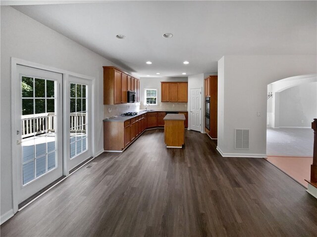 kitchen featuring open floor plan, brown cabinetry, light countertops, and a center island