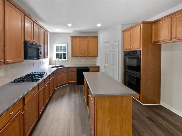 kitchen with dark wood-style floors, a kitchen island, brown cabinets, black appliances, and a sink