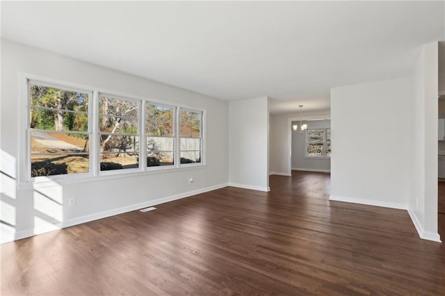 unfurnished room with a chandelier and dark hardwood / wood-style flooring