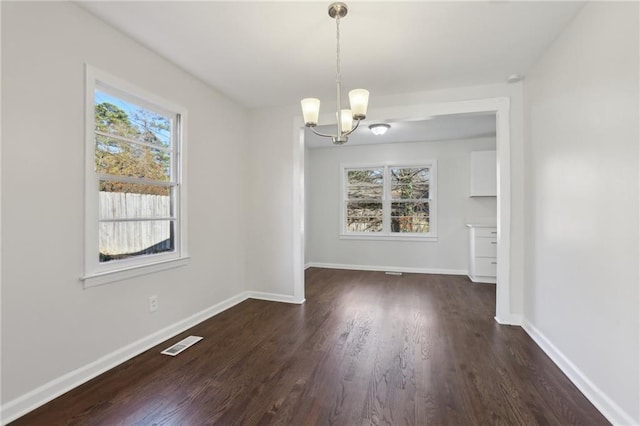 unfurnished dining area with dark hardwood / wood-style flooring and a notable chandelier