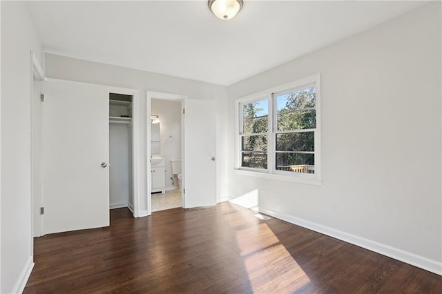 unfurnished bedroom with dark hardwood / wood-style flooring and ensuite bath