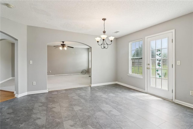 unfurnished dining area with visible vents, baseboards, a textured ceiling, arched walkways, and ceiling fan with notable chandelier