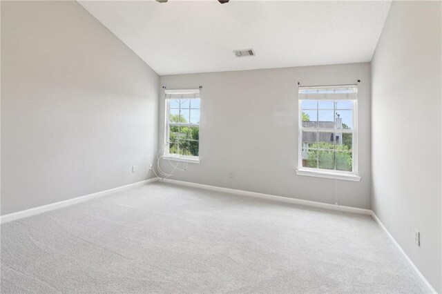 carpeted empty room featuring baseboards, ceiling fan, vaulted ceiling, and visible vents