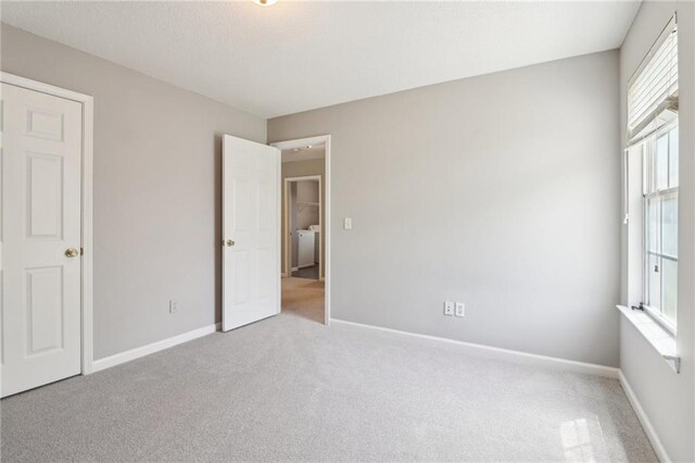 unfurnished bedroom with carpet floors, baseboards, and multiple windows
