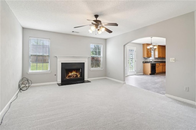 unfurnished living room featuring arched walkways, visible vents, a wealth of natural light, and light colored carpet