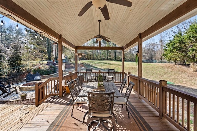 wooden deck with an outdoor fire pit, a lawn, and ceiling fan