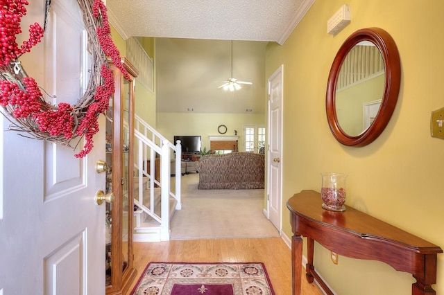 foyer entrance featuring crown molding, stairway, ceiling fan, a textured ceiling, and wood finished floors