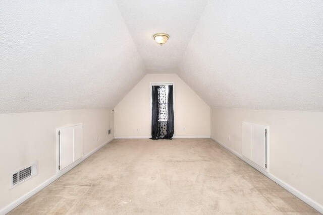 living area with a chandelier, lofted ceiling, light carpet, and baseboards