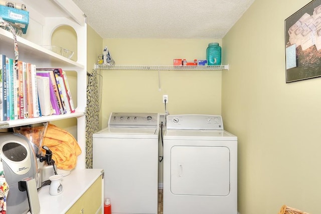 clothes washing area with laundry area, washing machine and dryer, and a textured ceiling