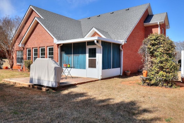 back of house with a yard, brick siding, roof with shingles, and a patio area