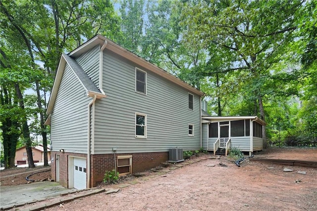 rear view of house with a sunroom, central air condition unit, and a garage