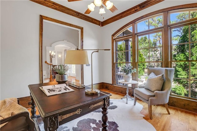 sitting room with a ceiling fan, crown molding, and wood finished floors