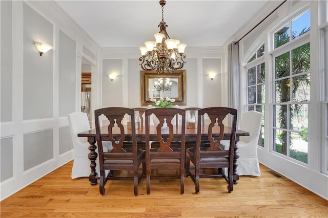 dining space with a decorative wall, a notable chandelier, light wood-style floors, and visible vents