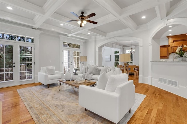living room featuring arched walkways, visible vents, french doors, and light wood-type flooring