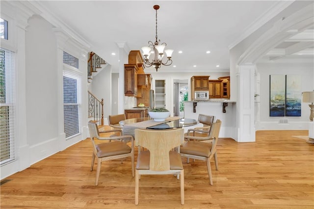 dining room featuring crown molding, stairway, a notable chandelier, and light wood-style flooring